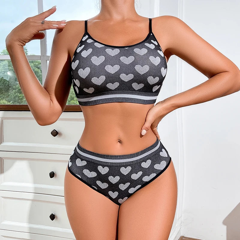 Person wearing a black sports bra and high-waisted underwear with heart pattern in a bright room.