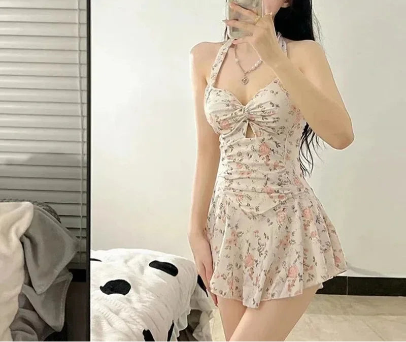 Woman taking a mirror selfie wearing a floral dress in a room.