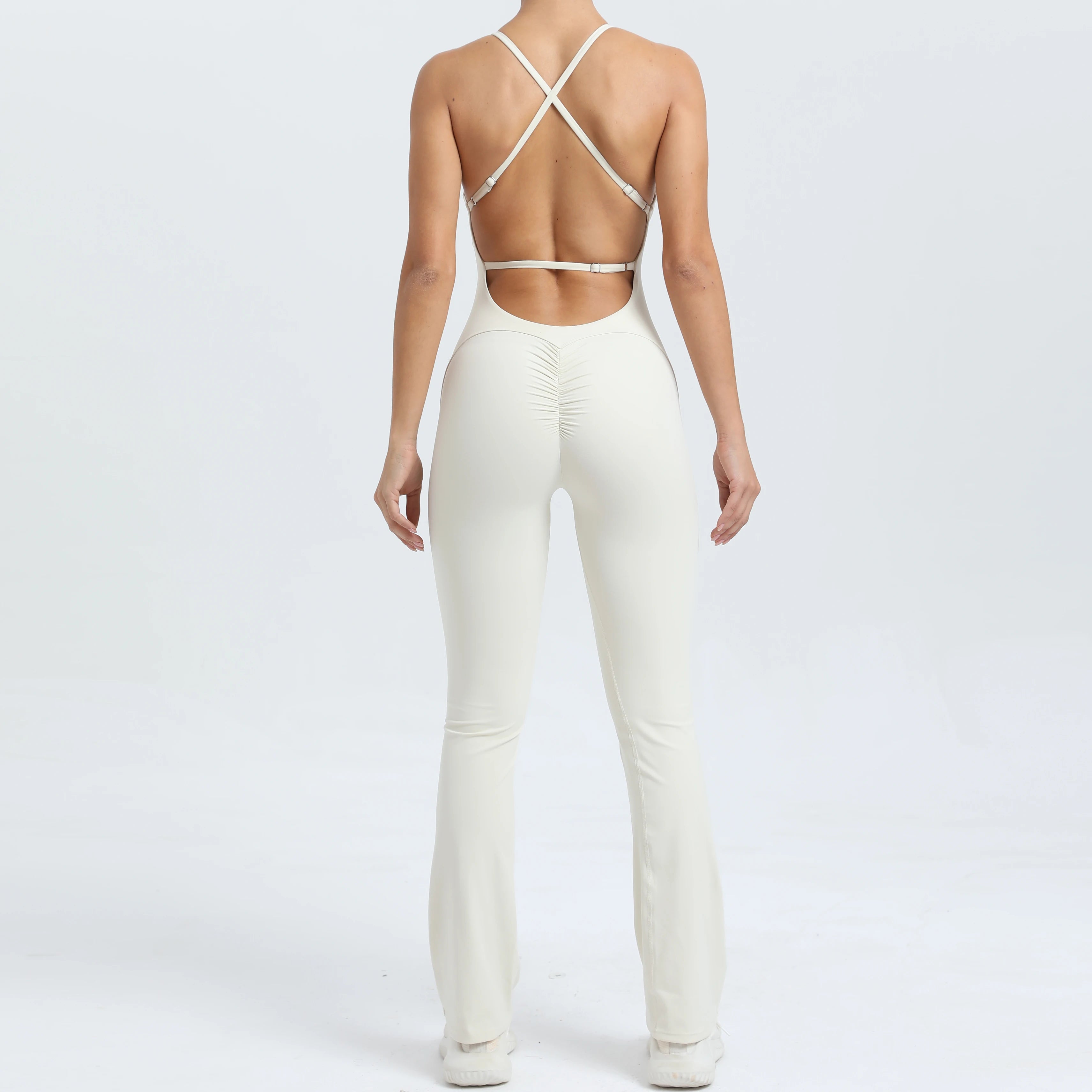 Person wearing a white outfit with a strappy top on a plain background