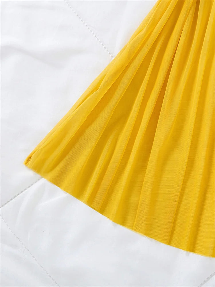 Close-up of the yellow pleated chemise skirt fabric and short hem.