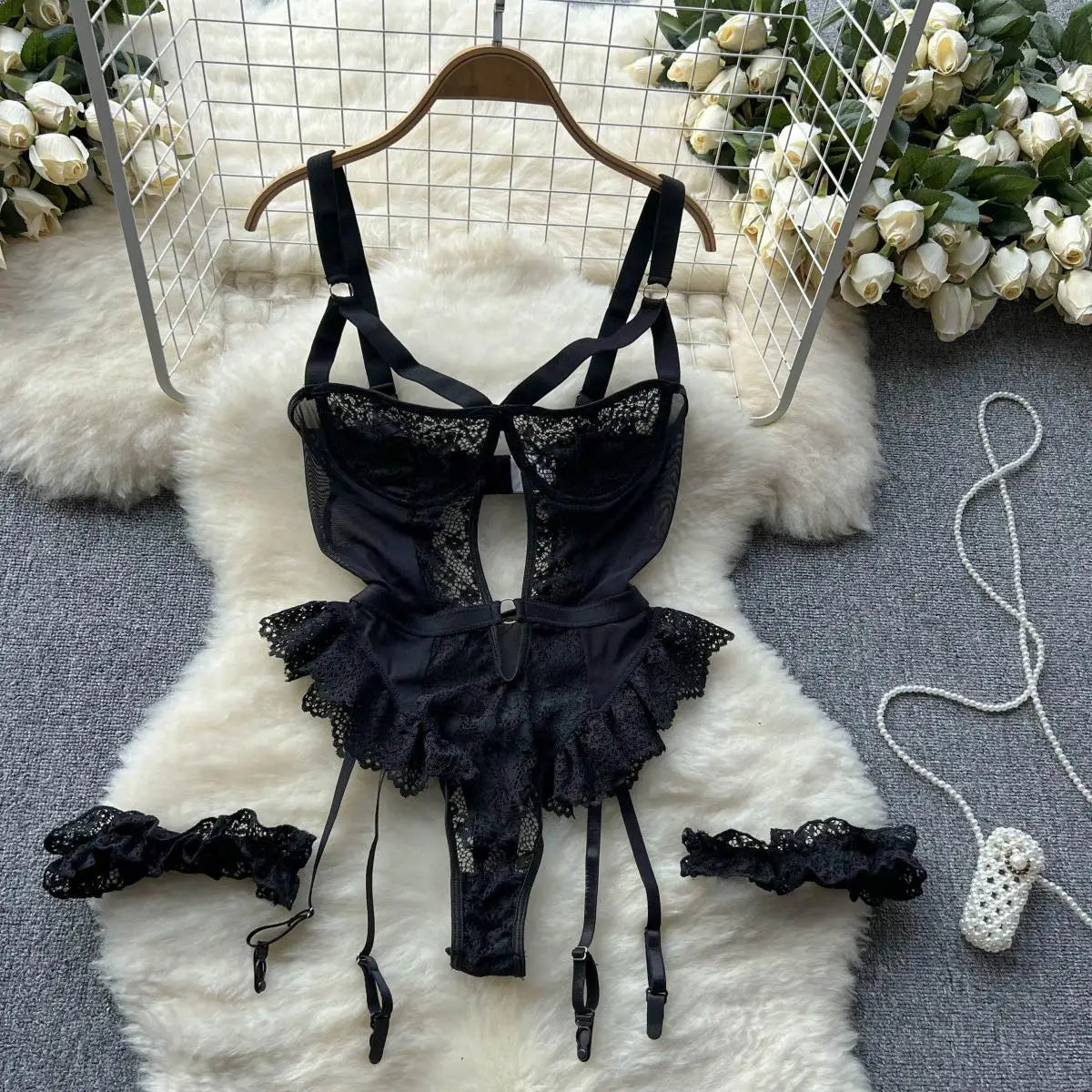 Black lace lingerie set on a white fur rug with floral decorations.