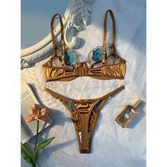 Gold bra set with floral details on a textured surface with a book and flower.