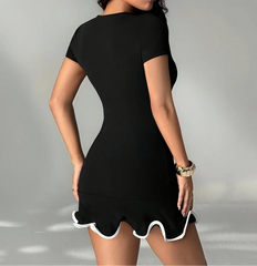 Woman wearing a black dress with white trim on a gray background