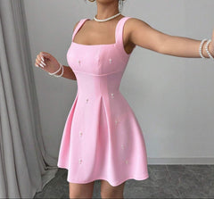 Woman wearing a pink dress with buttons against a gray background