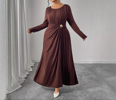 Woman wearing a brown long-sleeve dress in a minimalistic setting