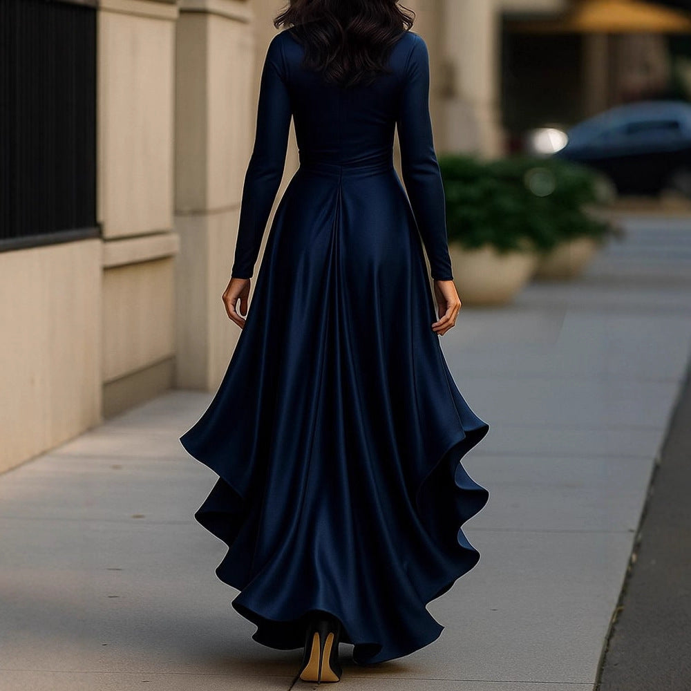 Woman in a long navy blue dress walking on a sidewalk.